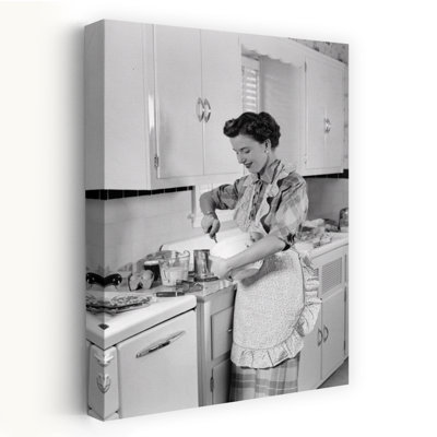 1950s WOMAN HOUSEWIFE IN KITCHEN APRON MIXING BAKING INGREDIENTS IN BOWL by H. Armstrong Roberts - Wrapped Canvas Print