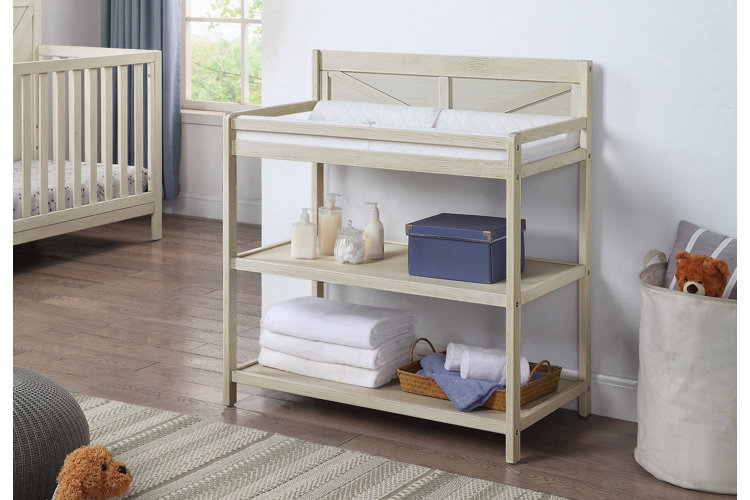 wood changing table in a pale blue nursery