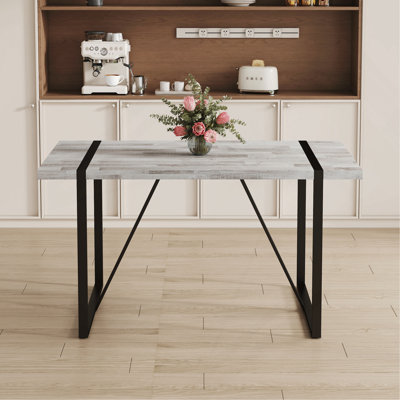 Une table de salle à manger rectangulaire rétro minimaliste avec un dessus spécialement texturé et des pieds en métal noir. Plateau de table contemporain en panneau de fibres à densité moyenne gris minimaliste.