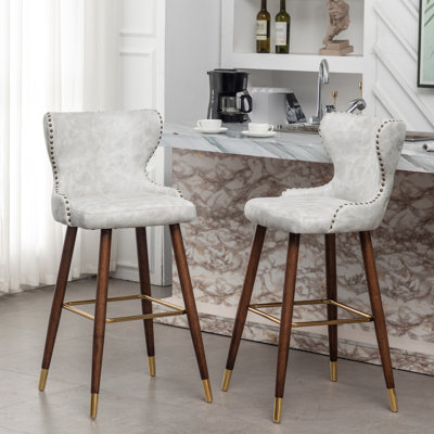 Mid-Century moderne 2. Similicuir avec tissu semblable au suède. Dossier à boutons et garniture de tête de clou courbée. Repose-pieds conique en bois massif au fini noyer massif et pieds dorés. Taille: l 19,75 po x P 21,5 po