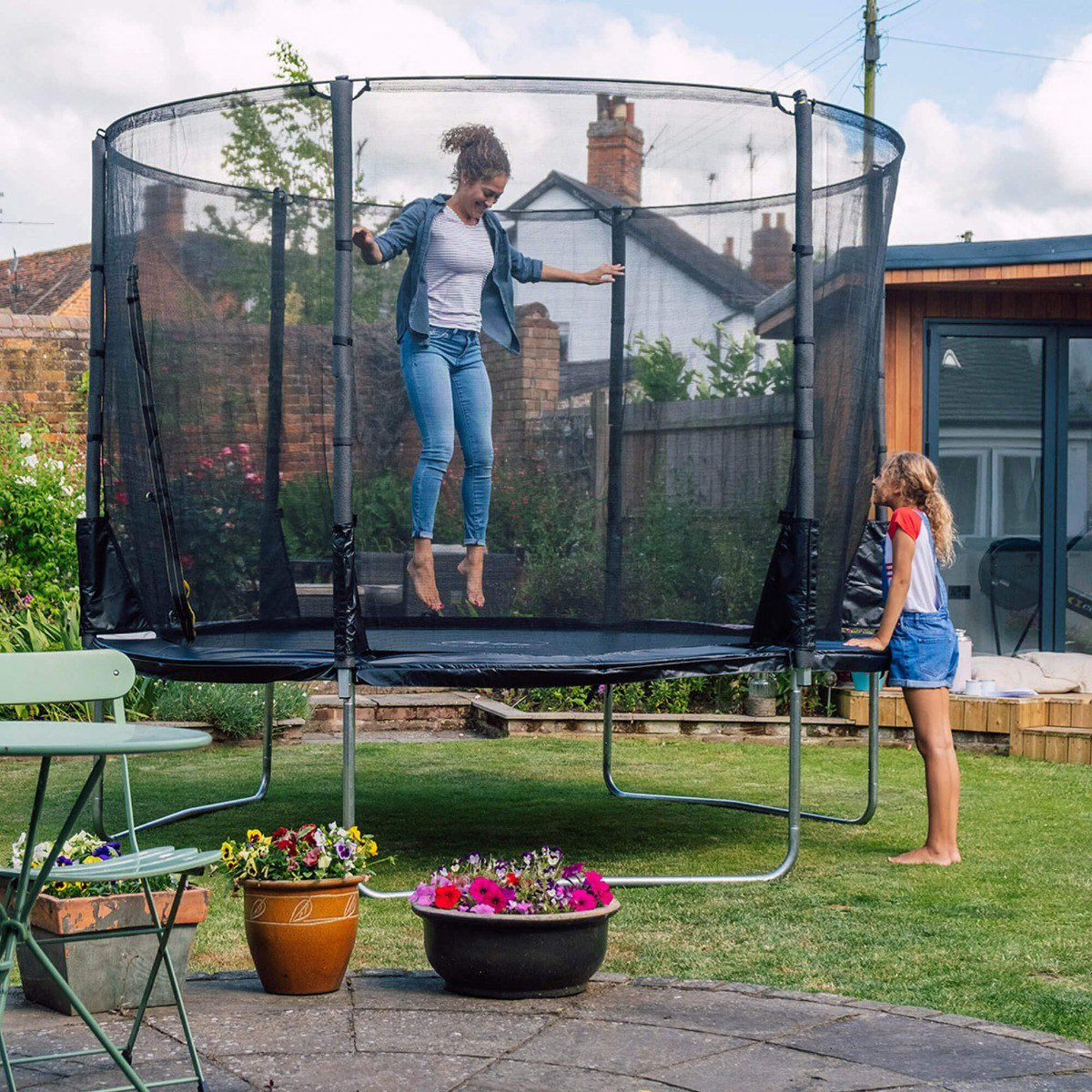 In ground clearance trampoline with enclosure