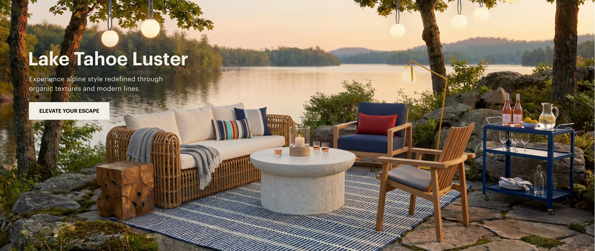 Outdoor patio furniture featuring a wicker sofa, concrete coffee table, and blue patterned rug set beside a lake at sunset with the text Lake Tahoe Luster and Elevate Your Escape.