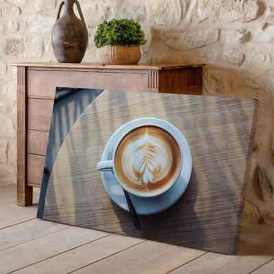 Toile vue de haut en bas d'un latté crémeux, art mural, une tasse en céramique blanche posée sur une surface en bois lisse et légère apportant une toile artistique chaleureuse