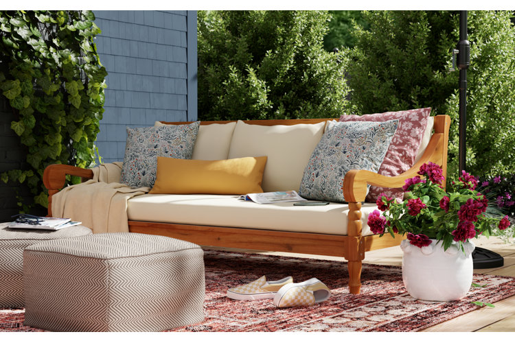 Cozy outdoor sofa with patterned pillows, soft cushions, and fresh flowers in a relaxed spring patio setting