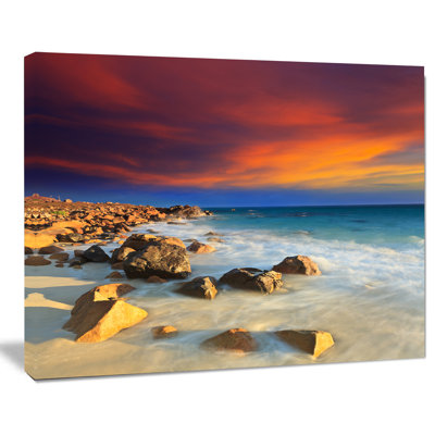 Plage avec des pierres sur le premier plan - reproduction de photo sur toile tendue