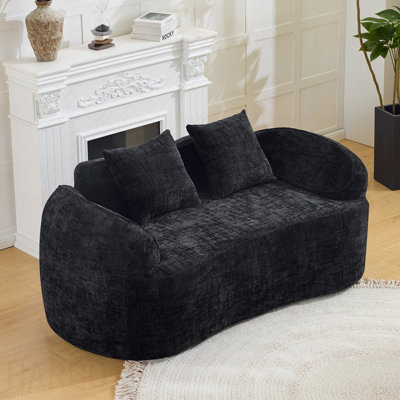 Black Curved two - person compress sofa. It has armrests on both sides, comes with two pillows, is  for small - sized apartments