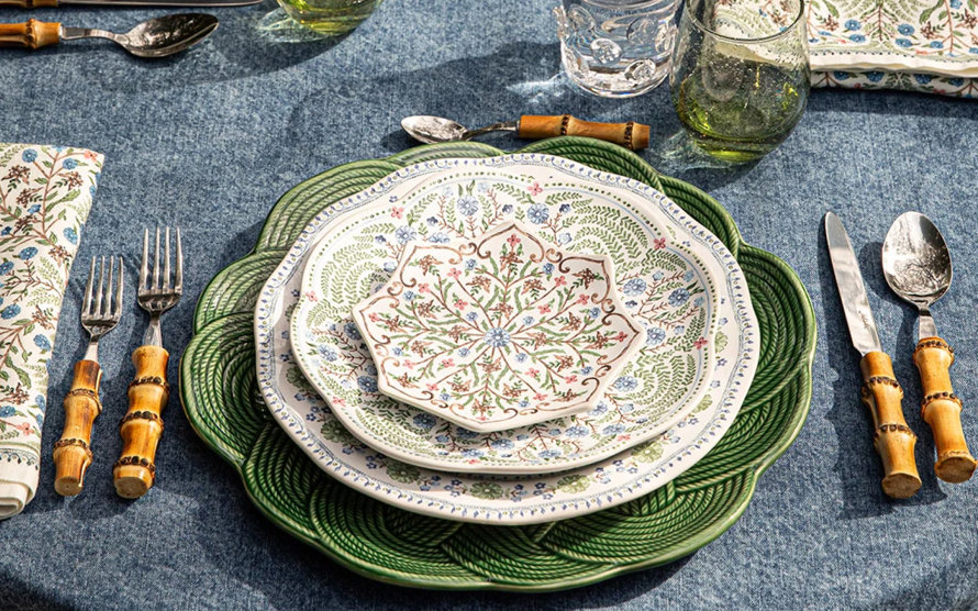 Table setting with floral patterned plates and bamboo flatware.