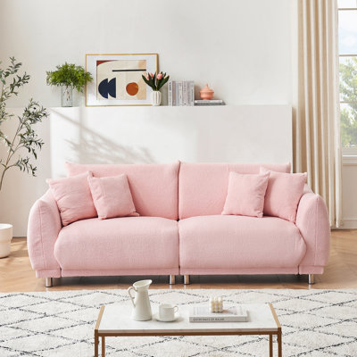Canapé confortable en molleton avec quatre coussins décoratifs et pieds de quincaillerie, idéal pour les chambres à coucher afin de maximiser l'utilisation de l'espace