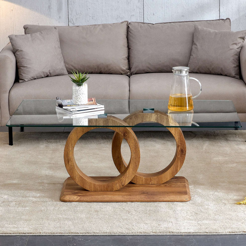 Une table basse rectangulaire moderne et tendance avec un plateau en verre trempé et des pieds en grain de bois. Convient au salon