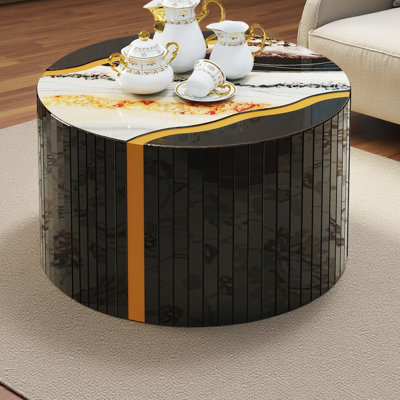 Table basse cylindrique noire et noire en verre noir avec miroir effet poudre dorée et motif de marbre sur la table d'appoint.