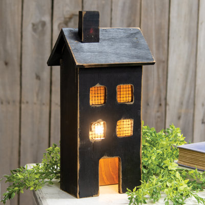 Maison éclairée en bois noir patiné