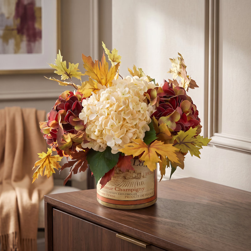 Composition d'hortensias et de feuilles d'automne dans un vase étiqueté