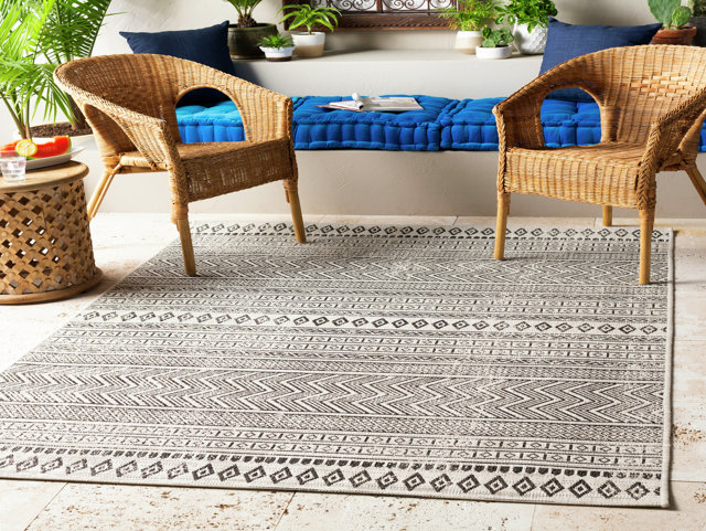 Outdoor rug on wooden dock with chairs overlooking autumn lake