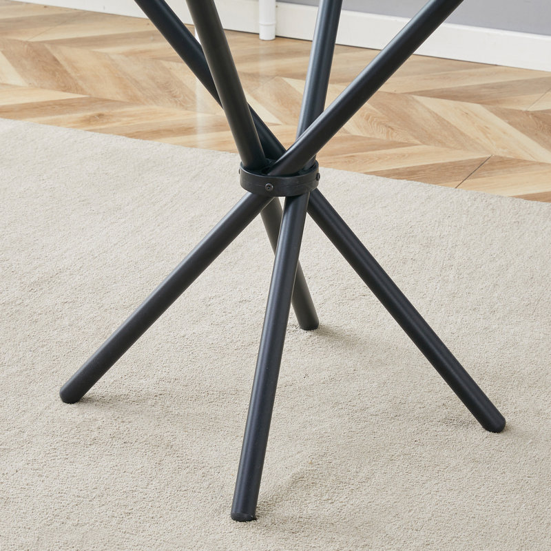 Table circulaire en verre trempé transparent avec pieds en métal noir entrelacés pour les espaces minimalistes modernes.