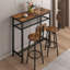 Ensemble de table haute de bar brun rustique et 2 tabourets. En fer. Structure robuste et stable. Pieds antidérapants. Tabourets pliables pour gagner de la place. Métal effet bois tendance.