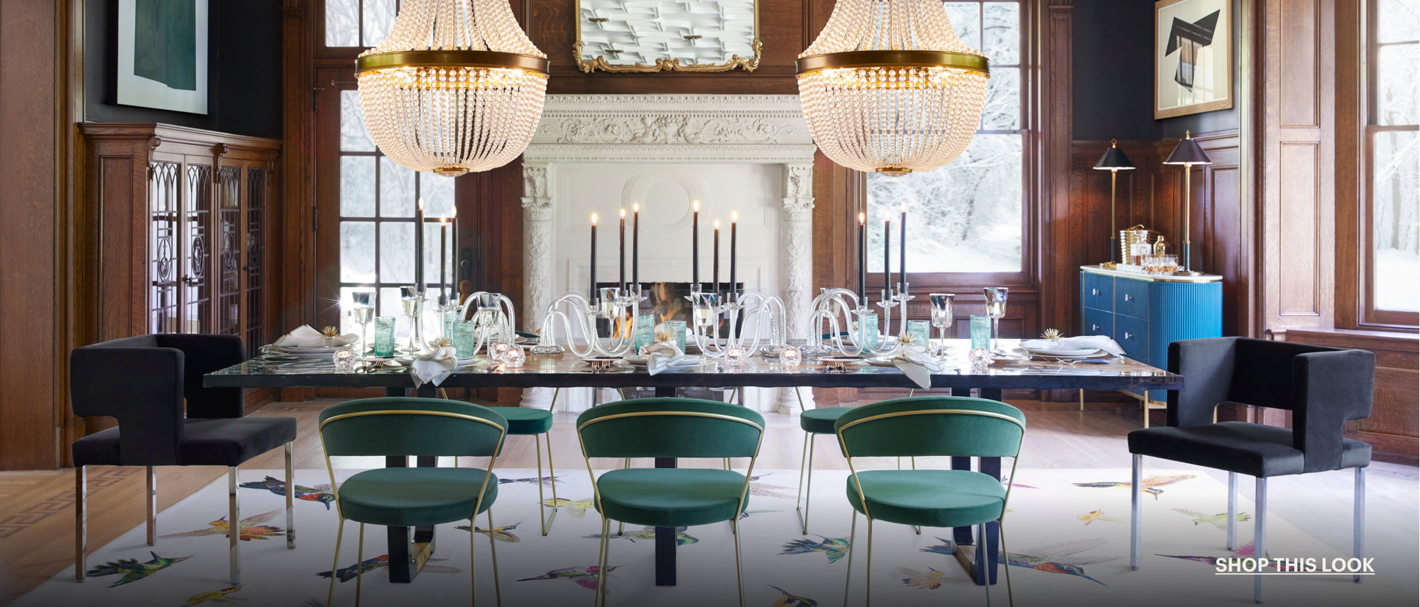 Formal dining room with two chandeliers, green chairs, and bird-patterned rug.