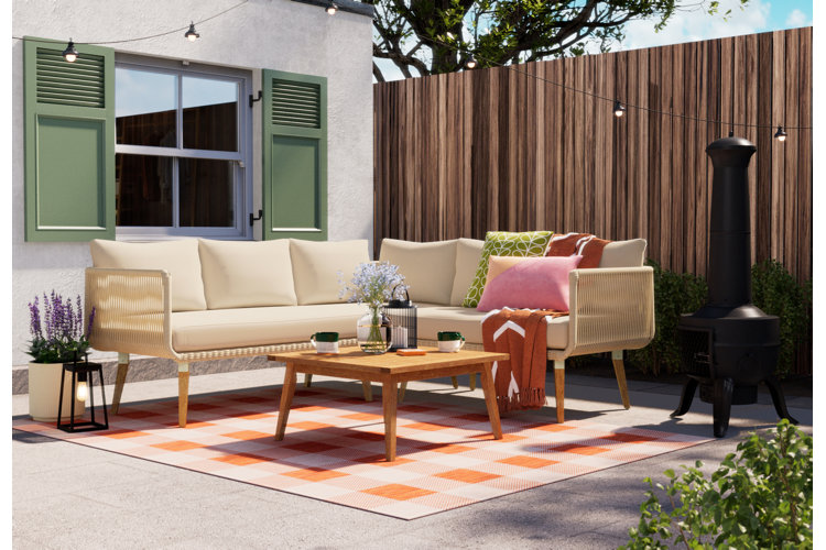 modern patio with a checkered orange patio rug beneath a wood outdoor sectional and matching coffee table