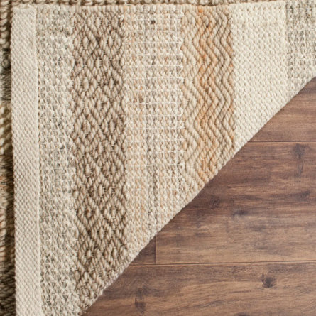 A textured rug in neutral colors sits on a hardwood floor.