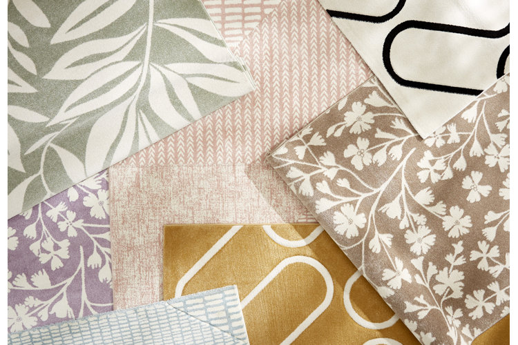 A flat lay collection of various rugs featuring soft pastel colors, floral patterns, geometric lines, and botanical designs