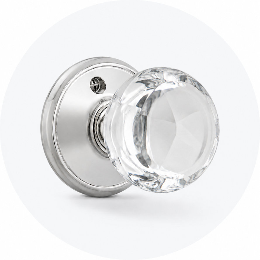 Polished chrome door knob with a round, faceted clear glass handle against a light gray circular background.