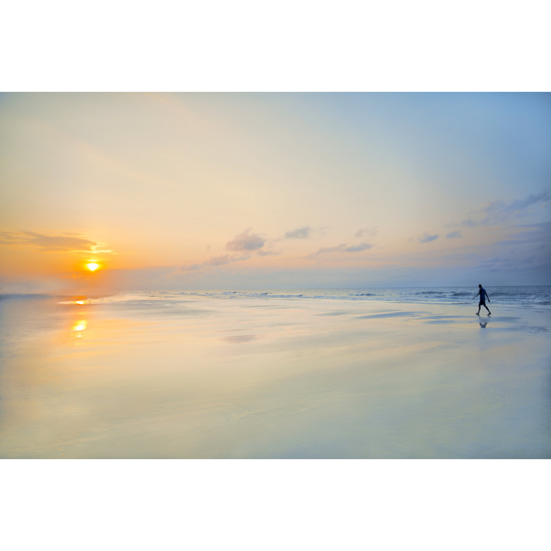 Mann geht bei Sonnenaufgang am Strand spazieren