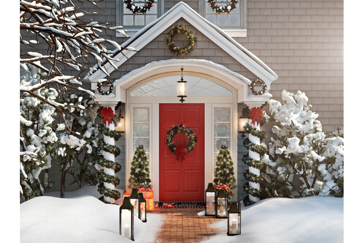 red front door with christmas wreath garlands on columns and lanterns lining a brick walkway