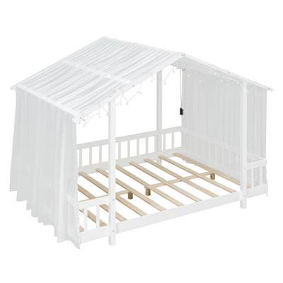 Lit plateforme avec auvent en tissu transparent et guirlandes de lumières, structure en bois en forme de maison avec garde-corps