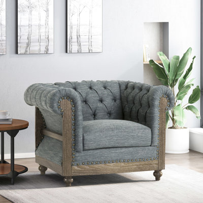 Fauteuil club à la mode avec tissu gris anthracite, capitonnage profond intense, volutes, détails cloutés, pieds en bouleau élégants gris anthracite, bouton complexe incurvé