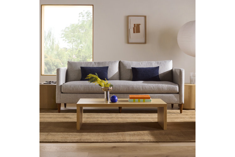 mid-century modern living room with a gray sofa, wood coffee table, jute area rug, and a gray accent chair