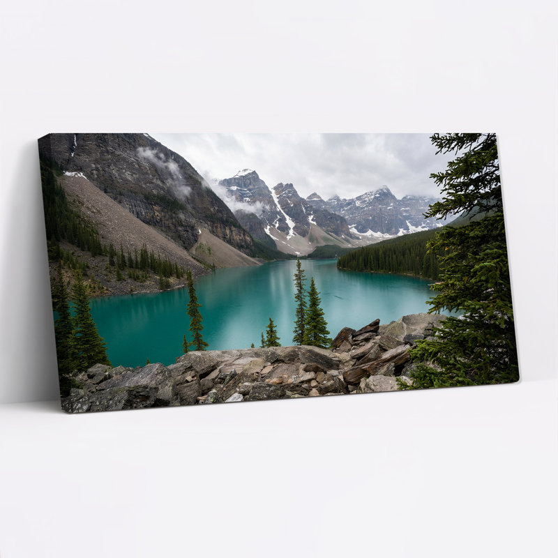 Tableau sur toile représentant un lac de montagne turquoise avec des sommets enneigés et des pins, 20"W x 10"H