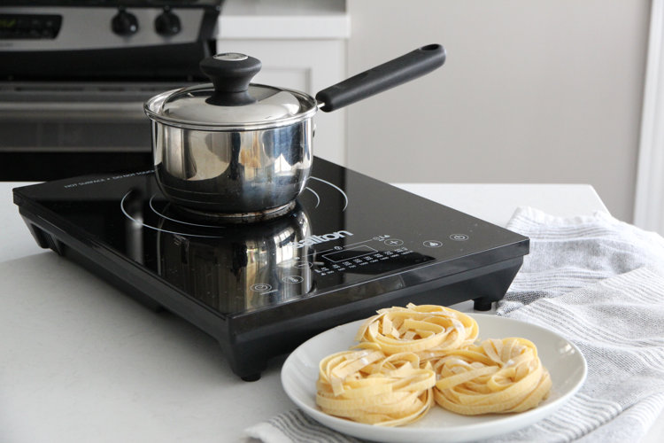 singleburner hot plate with a small pot next to a plate of pasta