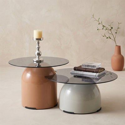 Deux tables basses gigognes - une grise avec un plateau en verre et une table d'appoint ronde brune - parfaites pour le salon ou le bureau