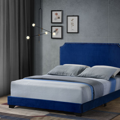 Grand lit Haemon en velours bleu avec garniture cloutée, pieds en bois et design entièrement rembourré pour un confort élégant