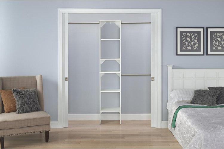 small bedroom closet with a central shelving unit and double hanging rods on each side for organizing clothes in a compact space