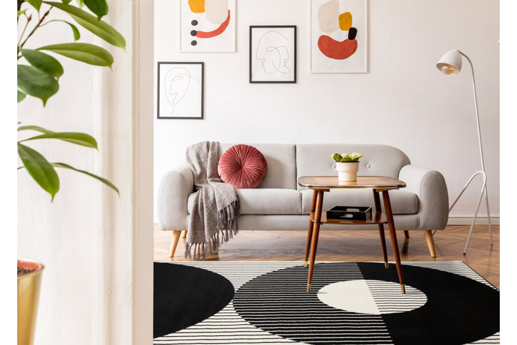 Modern living room with a neutral sofa, abstract art, and a bold patterned rug.