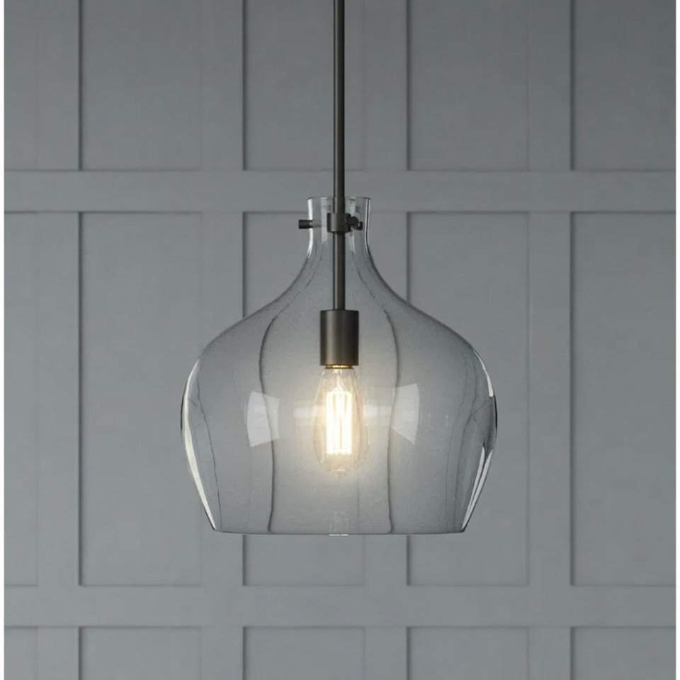 Modern clear glass teardrop pendant light with a black metal downrod hanging above a dining table with blue decor and grey upholstered chairs.