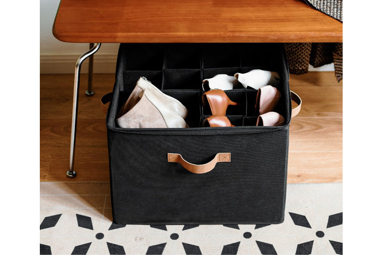 A black fabric bin with individual slots for shoes pulled out from under a wooden entryway bench.