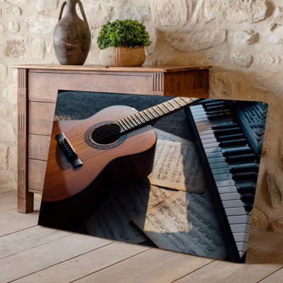 Toile, art rapproché d'une guitare acoustique en bois posée sur une surface texturée entourée de feuilles éparses, art mural