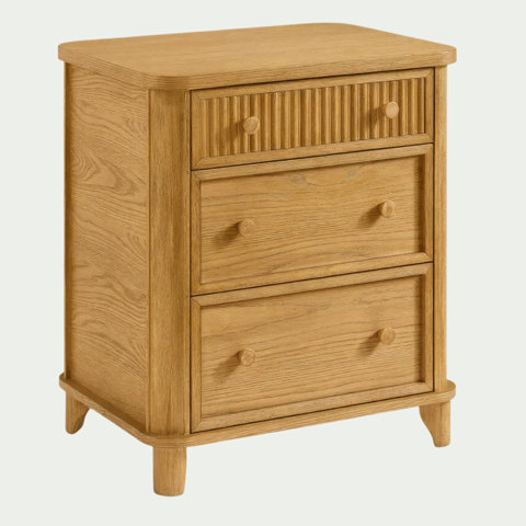 Light oak nightstand with three drawers featuring a fluted top drawer panel and rounded wooden knobs.