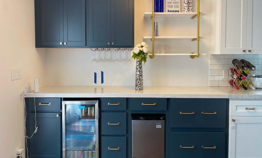 Bar area with navy and white cabinets and open shelving. On the shelving is an art piece that reads, "do what makes your soul happy".