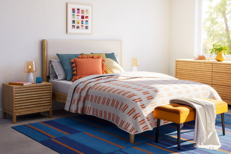 modern bedroom with a wood-and-upholstered bed, geometric-patterned comforter, colorful throw pillows, and a blue area rug