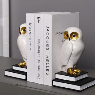 'a white and gold owl figurines on a stack of books'