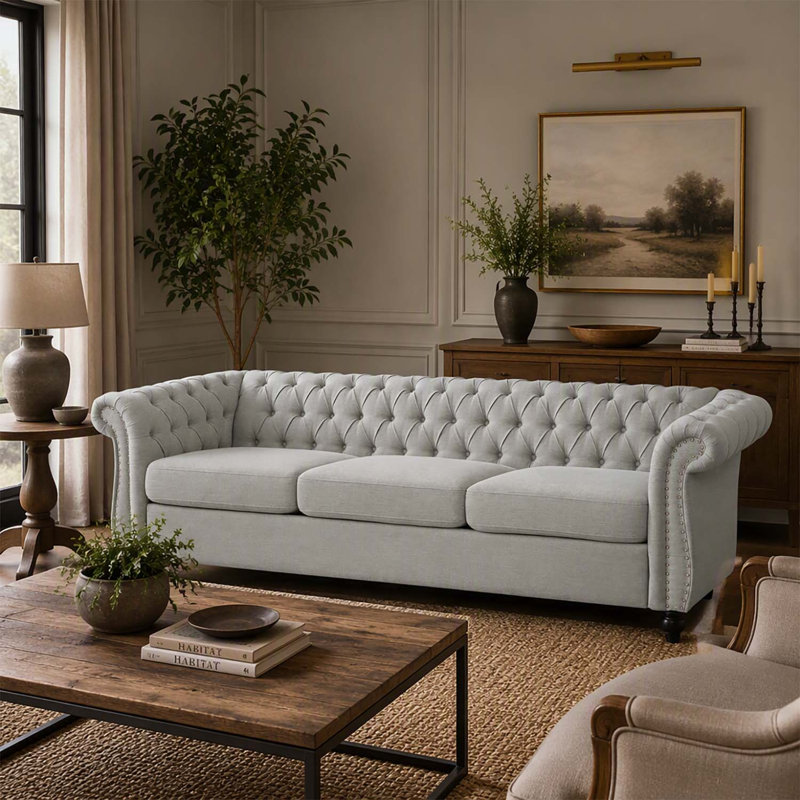 Canapé 3 places de style Chesterfield avec capitonnage à boutons, clous décoratifs et accoudoirs sculptés pour des espaces de vie élégants.