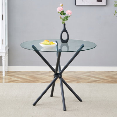 Une table ronde en verre trempé transparent d'un diamètre de 36,6 pouces, avec des pattes en métal noir en forme d'anneau.