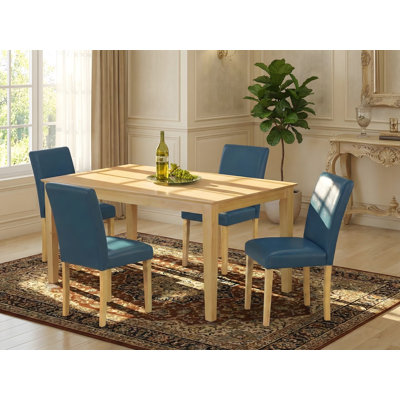 Cet ensemble de salle à manger 5 pièces comprend une table de salle à manger rectangulaire et 4 chaises Parson revêtues de similicuir Oasis