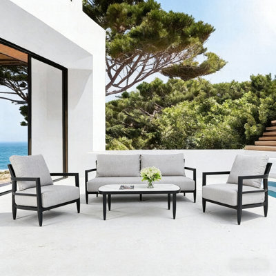 Ensemble de conversation extérieur 4 pièces avec fauteuils club modernes, canapé luxueux avec banc, table basse en pierre frittée d'inspiration marbre, structure en aluminium noir antirouille Ember et coussins Sunbrella