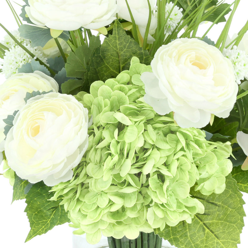 Renoncule, hortensia et herbe disposés dans un vase en verre
