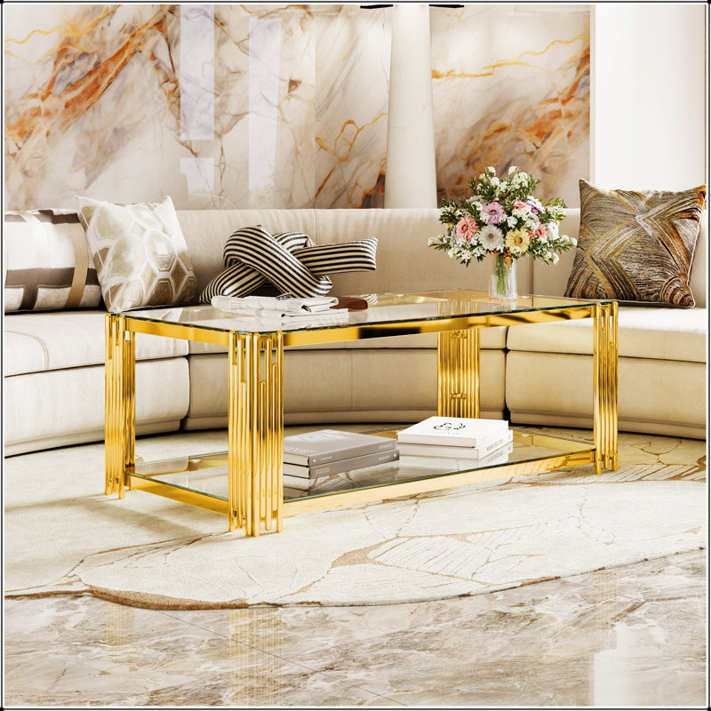 Table basse moderne en verre transparent avec structure asymétrique en métal, finition dorée et tablette inférieure pour un rangement élégant