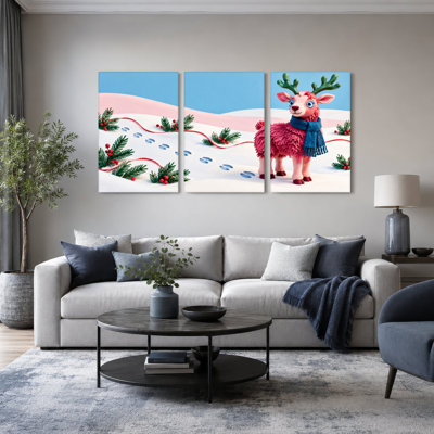 Ensemble de 3 toiles murales représentant un renne rose avec un foulard bleu dans un décor de Noël enneigé