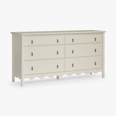 Commode Onda en bois massif à 6 tiroirs avec poignées en métal, fini ivoire et base festonnée, idéale pour une chambre de style campagnard.